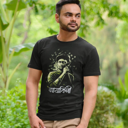 Man wearing a black t-shirt with a graphic design in a green outdoor setting